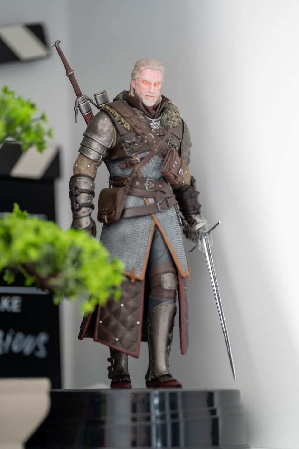 Sculpted swordsman figure in leather armor and chainmail holding a sword, standing on a glossy black display base