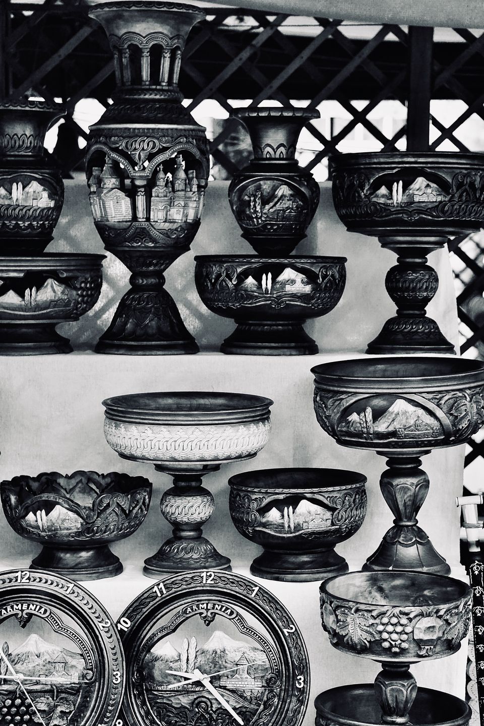 Black and white photo of carved wooden pedestal bowls and vases decorated with mountain scenes